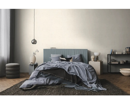 Moderne, lichte slaapkamer met een bed met een blauw, verticaal geribbeld hoofdbord, blauw beddengoed en een visgraatparketvloer.