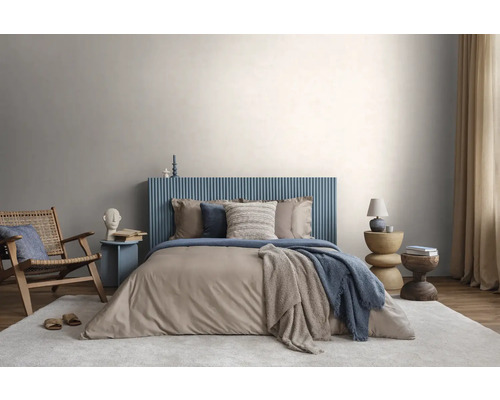 Moderne slaapkamer met blauw geribbeld hoofdbord, beige beddengoed, houten stoel en licht vloerkleed tegen een lichtgrijze muur.