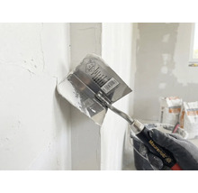 Maurerlob hoektroffel bij het aanbrengen van plamuur in een binnenhoek.