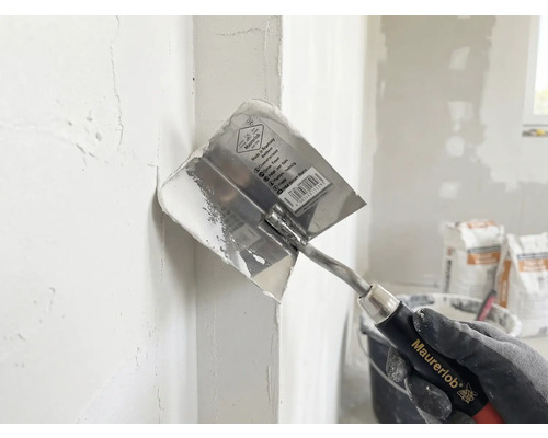 Maurerlob hoektroffel bij het aanbrengen van plamuur in een binnenhoek.