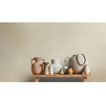 Beige vliesbehang met verticale structuur achter een selectie keramieken vazen op een rustieke houten bank.