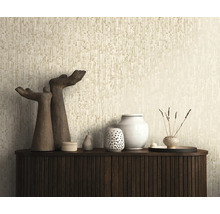 Gestructureerd behang met een verticaal patroon in beige achter een donker dressoir met decoratieve objecten en sculpturen.