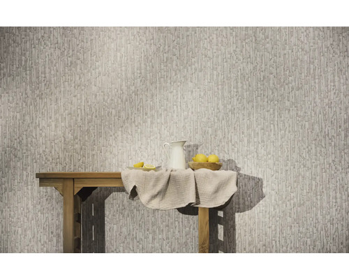 Vliesbehang met een abstract, verticaal patroon op een muur achter een houten tafel met een kan en citroenen.