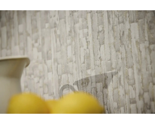 Vliesbehang met gestructureerd steenpatroon in grijs en beige met een subtiel silhouet van een kan.