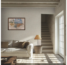Lichte woonkamer met behang met textuur, witte bank, bruine kussens, houten vloer, tafellamp op een mand en een trap.