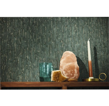 Donkergroen vliesbehang met een verticale structuur op een wand achter een houten plank met een zoutlamp kaars en glas.