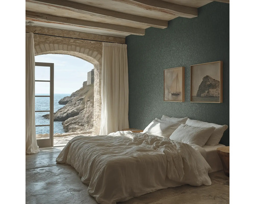 Slaapkamer met donkergroen structuurbehang, wit bed, plafond met houten balken en een stenen boog met uitzicht op zee.
