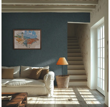Heldere woonkamer met donkerblauw structuurbehang op de muur, een witte bank en zonlicht op de houten vloer.