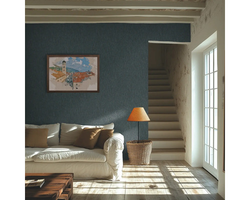 Heldere woonkamer met donkerblauw structuurbehang op de muur, een witte bank en zonlicht op de houten vloer.