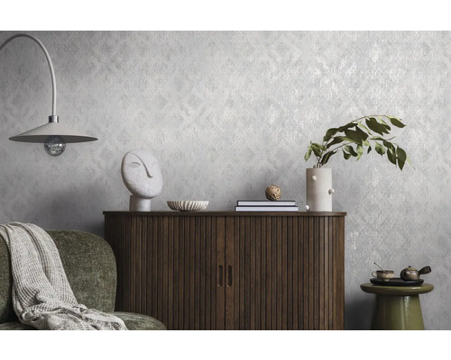 Gestructureerd vliesbehang met een subtiel patroon op een wand achter een houten dressoir en decoratie in een modern ingerichte woonkamer.