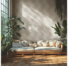 Lichte woonkamer met behang met palmbladmotief, een lage houten bank met kussens, kamerplanten en zonlicht op de houten vloer.