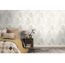 Lichte slaapkamer met vliesbehang met palmbladmotief, een bed met kussens en een nachtkastje met lamp.