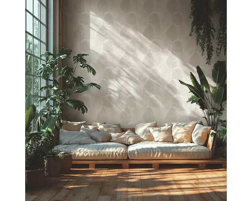 Lichte woonkamer met behang met bladpatroon, een houten bank met veel kussens en diverse kamerplanten op een houten vloer.