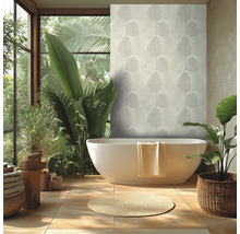 Heldere badkamer met wit vrijstaand bad, behang met palmbladmotief, grote groene kamerplanten en een rond kleed van natuurlijke vezels.