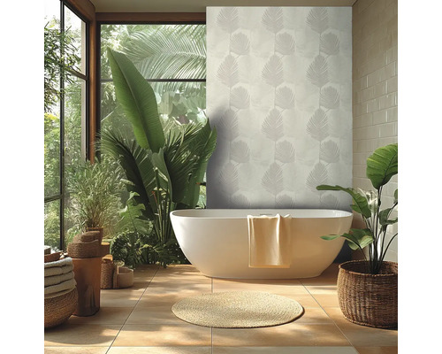 Heldere badkamer met wit vrijstaand bad, behang met palmbladmotief, grote groene kamerplanten en een rond kleed van natuurlijke vezels.
