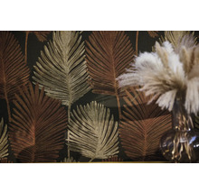 Vliesbehang met een groot patroon van palmbladeren in goud en brons op een donkere achtergrond.