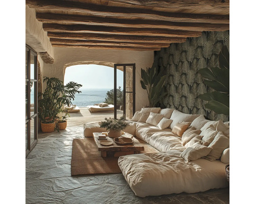 Lichte woonkamer in mediterrane stijl met grote bank, houten plafondbalken, natuurstenen vloer, behang met bladmotief en uitzicht op zee.