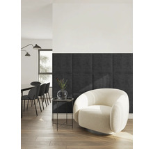 Moderne woonkamer met donkergrijze vierkante wandpanelen, een crèmekleurige fauteuil van bouclé stof en een zwarte bijzettafel op houten vloer.