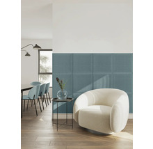 Moderne, lichte woonkamer met blauwe gestoffeerde wandpanelen van textiel achter een witte fauteuil.