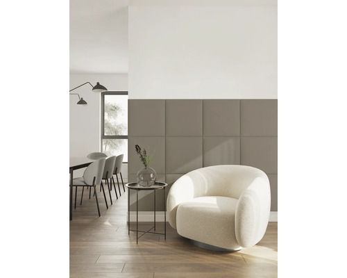 Moderne woonkamer met beige-bruine vierkante akoestische panelen aan de wand, een crèmekleurige fauteuil en een eethoek op de achtergrond.