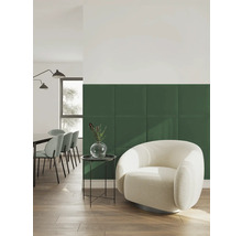 Moderne woonkamer met groene gestoffeerde wandpanelen, een lichte fauteuil, bijzettafel en eethoek op een houten vloer.