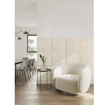 Moderne woonkamer met vierkante gepolsterde wandpanelen, een ronde fauteuil en een eethoek in een lichte, georganiseerde ruimte.