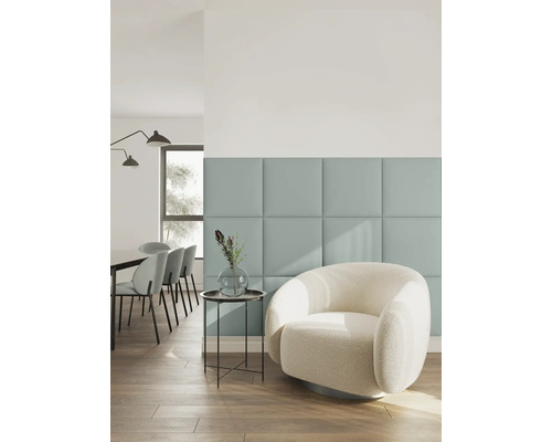 Moderne woonkamer met vierkante wandpanelen, een witte bouclé fauteuil, bijzettafel met vaas en eethoek op de achtergrond.