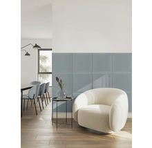 Vierkante gestoffeerde wandpanelen van stof in blauw in een lichte, modern ingerichte woonkamer met een witte fauteuil en houten vloer.
