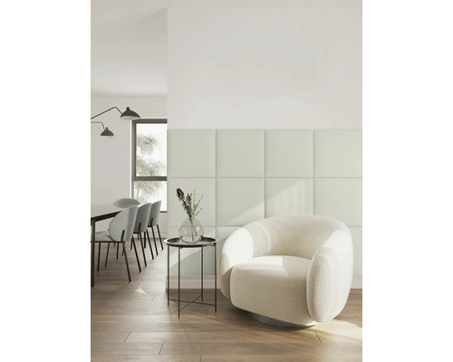 Modern, licht interieur met vierkante wandpanelen, een ronde fauteuil van bouclé en een eetgedeelte op de achtergrond.