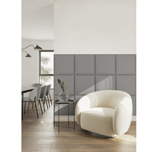 Moderne woonkamer met grijze vierkante gestoffeerde wandpanelen, een witte fauteuil en een bijzettafel op een houten vloer.