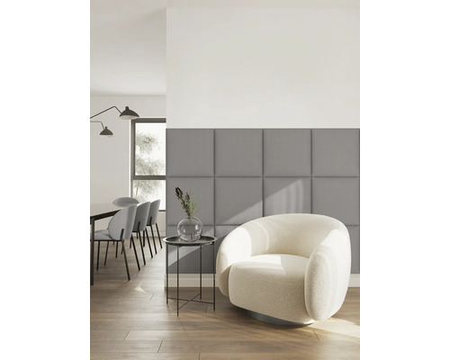 Moderne woonkamer met grijze vierkante gestoffeerde wandpanelen, een witte fauteuil en een bijzettafel op een houten vloer.