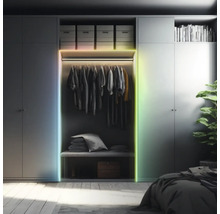 Ledstrip op een kledingkast in een georganiseerde slaapkamer. Meerkleurige verlichting aan het frame van de kast.