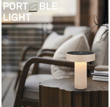 Draagbare LED-tafellamp met zonnepaneel op een houten bijzettafel in een sfeervolle buitenomgeving op een terras.