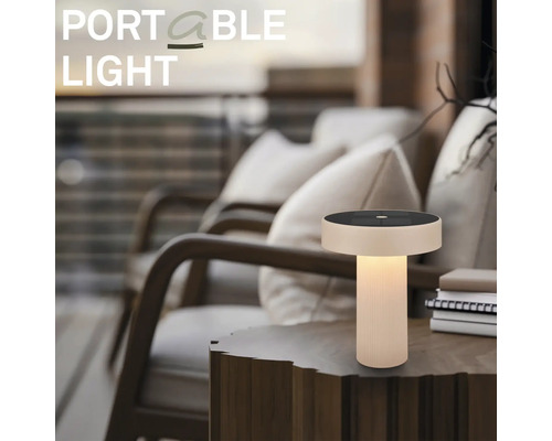 Draagbare LED-tafellamp met zonnepaneel op een houten bijzettafel in een sfeervolle buitenomgeving op een terras.