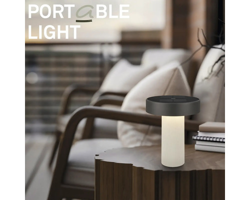 Draagbare LED-tafellamp op een houten tafel in een moderne buitenruimte met comfortabele fauteuils.