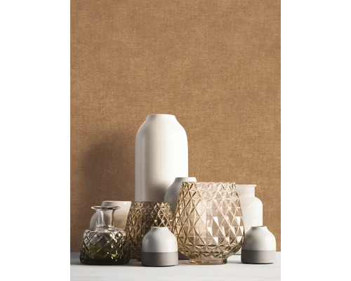 Effen gestructureerd behang in beige achter een decoratieve groep van diverse witte en glazen vazen.