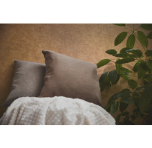 Twee sierkussens en een deken met textuur voor behang met patroon naast een kamerplant.