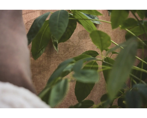 Gestructureerd behang in bruine textiel look met groene plantenbladeren op de voorgrond