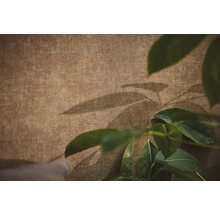 Gestructureerd behang met linnenlook en decoratieve schaduwen van bladeren.