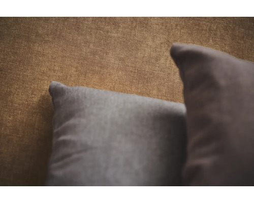 Detailopname van behang met textiellook en twee decoratieve kussens.