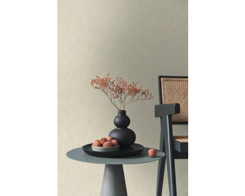 Gestructureerd vliesbehang in beige in een moderne woonkamer met bijzettafel, vaas met droogbloemen en stoel.