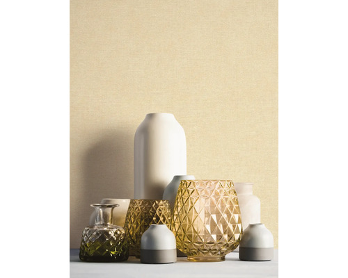 Fijn gestructureerd behang in lichtbeige achter een groep decoratieve vazen van glas en keramiek.