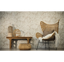 Woonkamer met vliesbehang met waaiermotief, rotan stoel met plaid, houten bank met lantaarns en een gevlochten mand op de vloer.