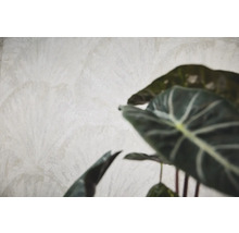 Gestructureerd vliesbehang met subtiel palmbladmotief in beige en kamerplant op de voorgrond.