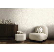 Moderne woonkamer met licht behang met patroon, donker houten dressoir, lichte gestoffeerde fauteuil en bijpassende hocker.