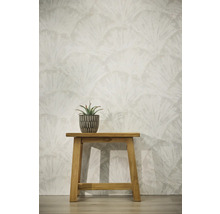 Behang met waaiervormig bladerpatroon, houten krukje met vetplant in pot tegen een lichte wand.