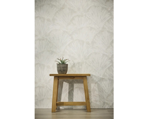 Behang met waaiervormig bladerpatroon, houten krukje met vetplant in pot tegen een lichte wand.