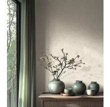 Lichte woonkamer met houten dressoir, groene keramische vazen met takken voor een muur met structuurverf en gordijnen.