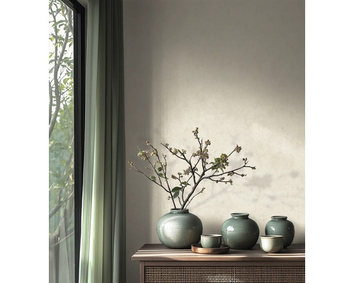 Lichte woonkamer met houten dressoir, groene keramische vazen met takken voor een muur met structuurverf en gordijnen.