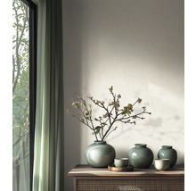 Ronde keramische vazen met craquelé glazuur en takken op een houten sidetable in een modern ingerichte kamer naast een raam.